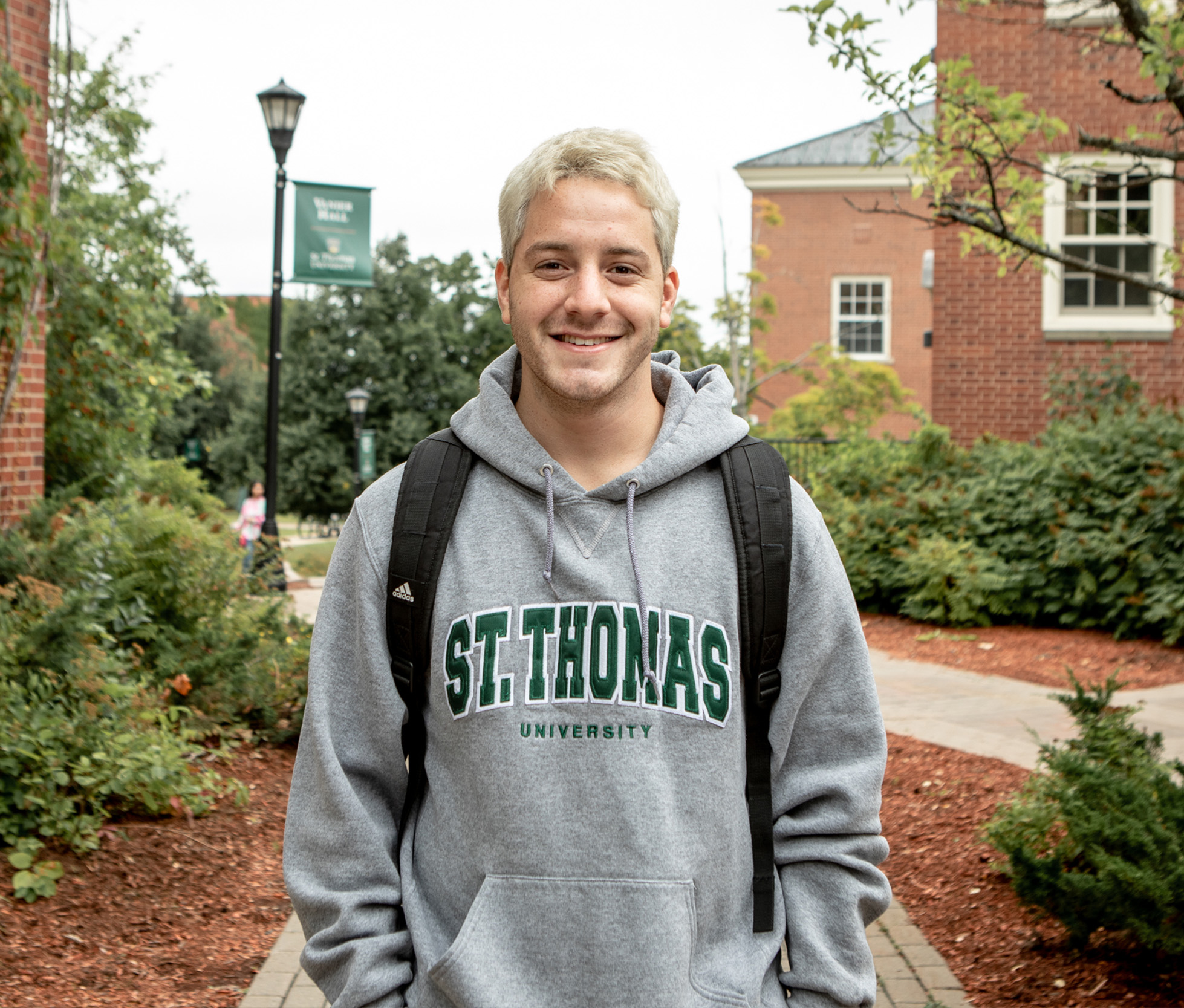 A male student wearing a St. 蜜桃視頻_蜜桃視頻APP_蜜桃視頻官网 sweater, smiling on campus