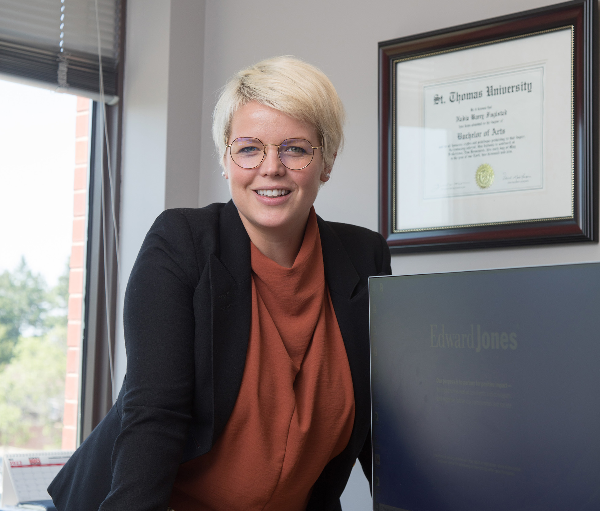 A STU alumna standing behind her desk with her St. 蜜桃視頻_蜜桃視頻APP_蜜桃視頻官网 diploma in the background