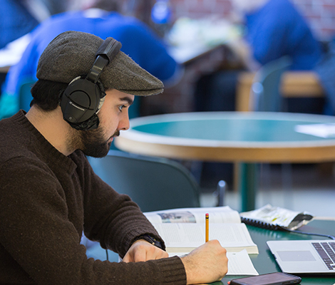 A student with headphoness on taking notes